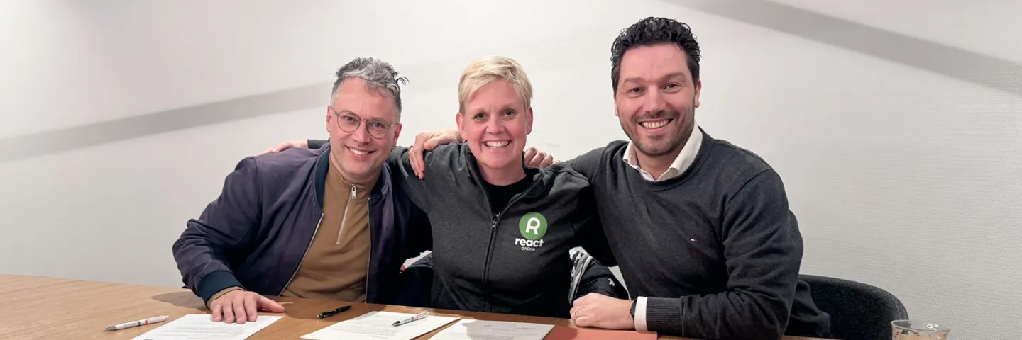 Three smiling people at a table with papers in front of them
