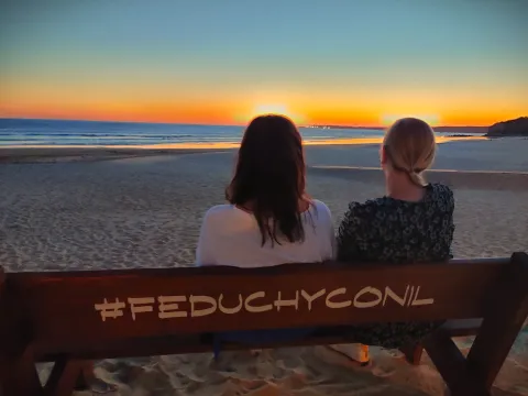 Karin and Sveta enjoying the sunset sitting on a bench at the beach