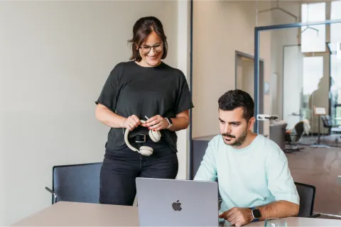 A man and a woman collaborating on a laptop in an office