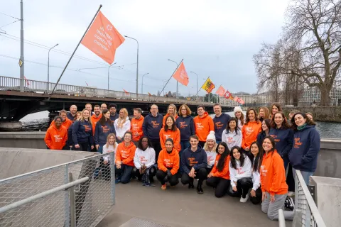 UICC team in orange and white clothing smiling on the bridge with WCD flags